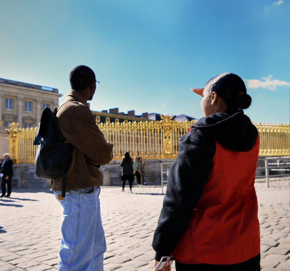Person with a guide at the entrance to the Palace of Versailles